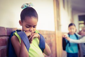 Sad pupil being bullied by classmates at corridor