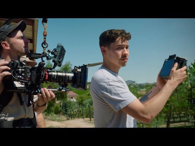 Filmteam filmer en ung mann utendørs med profesjonelt kamera